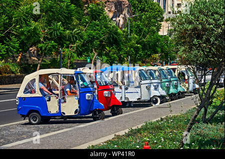 Funchal, Madeira e colorato tuk tuks sono allineati al lato della strada in attesa di locazione da turisti e visitatori della città. Foto Stock