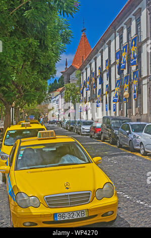 Funchal, Madeira e giallo taxi parcheggiato su una strada a ciottoli nel centro della citta'. Foto Stock