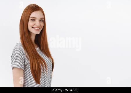 Sicuri di sé motivato redhead talentuoso studentessa occhi blu a strisce che indossa la t-shirt profilo permanente girando fotocamera a sorridere un aspetto professionale con Foto Stock