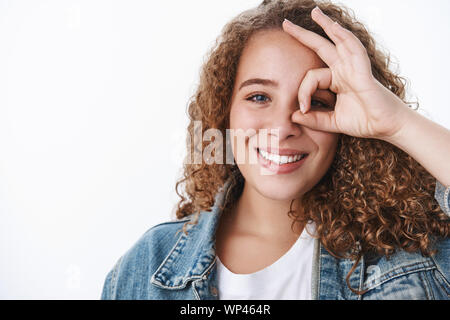 Close-up carismatico positivo vivace giovani fiduciosi morbidi ricci di donna dai capelli visualizza ok ok gesto perfetto occhio guardare attraverso felicemente sorridendo allegro h Foto Stock