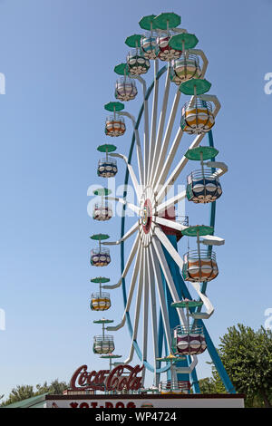 Una grande ruota panoramica Ferris in un parco di divertimenti a Bukhara, Uzbekistan. Una Coca-Cola pubblicità segno nella parte inferiore dell'immagine. Foto Stock