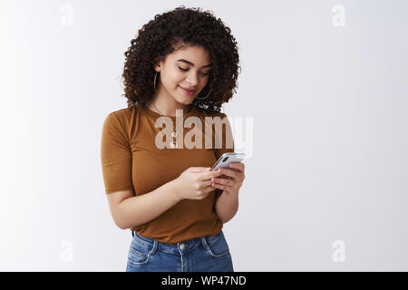 Elegante ragazza moderna controllo cassetta postale dello smartphone di contenimento guardare lo schermo del telefono visualizza sorridendo felice messaging scrivere post social media pagina fe di scorrimento Foto Stock