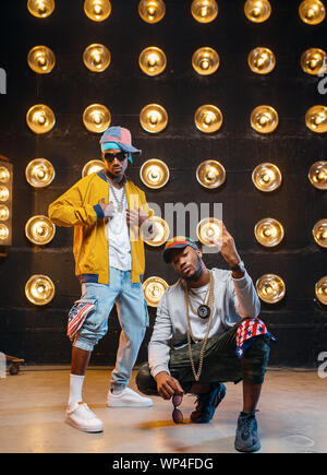 Rappers in caps danza sul palco con faretti Foto Stock