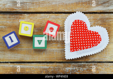 Blocchi di legno con lettere di amore e di rosso cuore di maglia Foto Stock