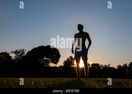 Un ragazzo cattura e passare una palla da rugby su un giorno d'estate in un parco, la formazione per la nuova stagione Foto Stock