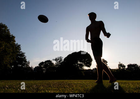 Un ragazzo cattura e passare una palla da rugby su un giorno d'estate in un parco, la formazione per la nuova stagione Foto Stock