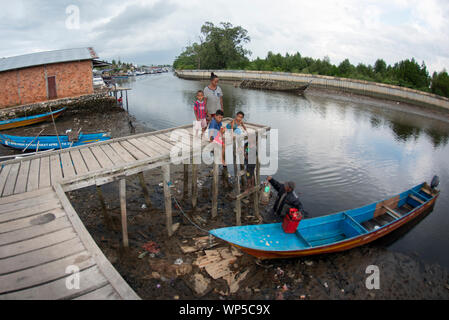 Famiglia lo scarico di merci dalla canoa sul molo sul fiume, Sorong, Papua occidentale, in Indonesia Foto Stock