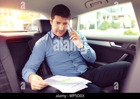 Sorridenti business man parlando al telefono mentre la localizzazione in un taxi Foto Stock
