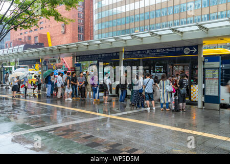 Fukuoka, Giappone - 13 Luglio 2019 - Il popolo giapponese attendere i loro autobus alla fermata vicino alla stazione di Hakata a Fukuoka, Giappone sulla luglio 13, 2019 Foto Stock