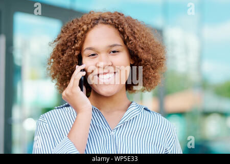 Giovane imprenditrice allegro con parentesi marrone capelli parlando sullo smartphone Foto Stock