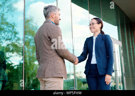 Felice giovane imprenditrice agitando la mano del suo cliente dopo la trattativa Foto Stock