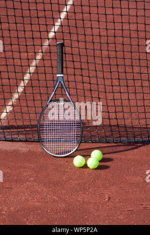 Ancora la vita di palle da tennis e una racchetta su un campo da tennis in argilla rossa. Foto Stock