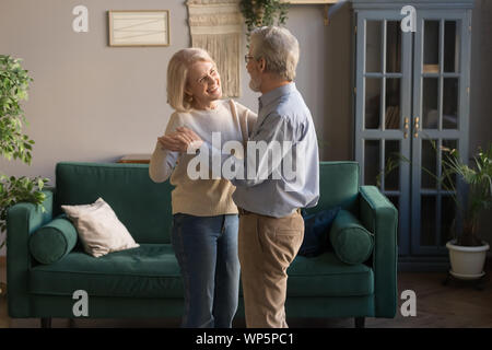 Sorridenti sposi anziani ballare waltzing a casa Foto Stock