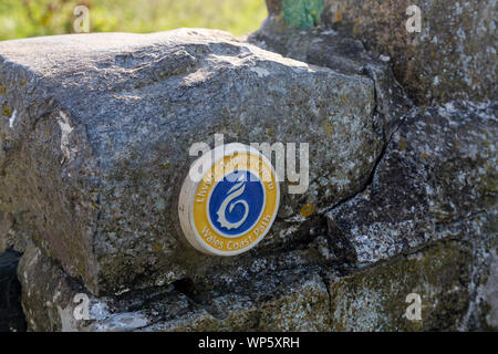 Un Wales coast Path marcatore in una parete vicino a Nash Point lighthouse che si affaccia sul Canale di Bristol, Glamorgan, Wales, Regno Unito Foto Stock