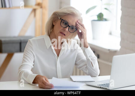 Malinconici senior donna pensando di soluzione del problema in ufficio Foto Stock