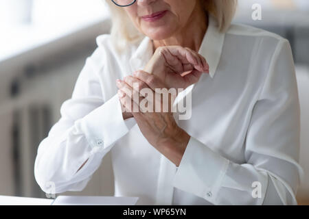Senior lavoratore di sesso femminile affetti da spasmo del polso o del ceppo Foto Stock