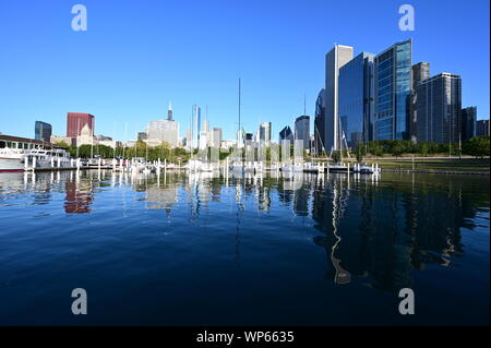 Chicago, Illinois 08-09-19 Chicago Yacht Club, barche e dello skyline della città si riflette sul tranquillo Lago Michigan in mattina presto luce estiva. Foto Stock