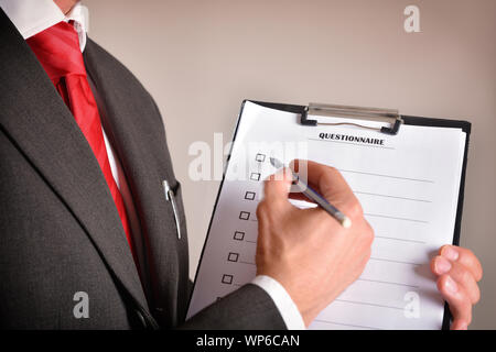 Uomo in tuta che mostra un questionario con i fogli in una cartella e una matita in mano. Composizione orizzontale. Vista laterale Foto Stock