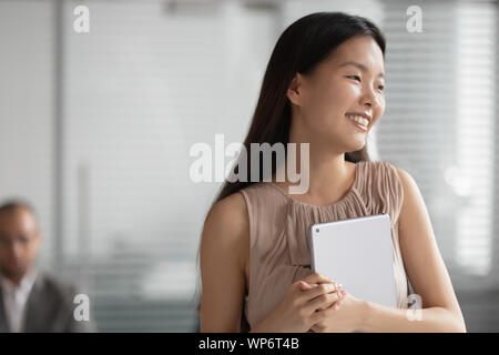 Colpo alla testa di giovani cinesi sorridenti dei dipendenti di sesso femminile che guarda lontano. Foto Stock