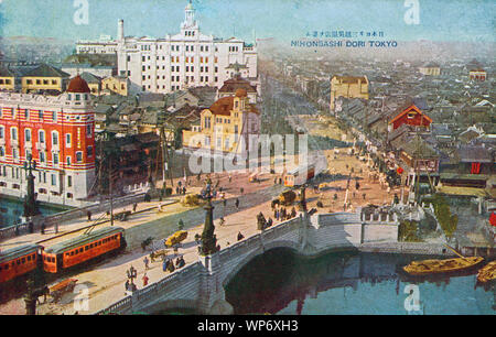 [ 1920s Giappone - Ponte Nihonbashi, Tokyo ] - Streetcars sul Ponte Nihonbashi a Tokyo, progettato da Yorinaka Tsumaki (妻木頼黄, 1859-1916). L'edificio rosso è la sede principale di Teikoku Seima Co., Ltd. (Ancora oggi attivo come Teikoku Sen-i Co., Ltd.). Completato nel 1913 (Taisho 2), fu progettato da Kono Tatsuno (辰野金吾, 1854–1919). L'edificio bianco al centro è il Mitsukoshi Department Store. cartolina vintage 20th secolo. Foto Stock