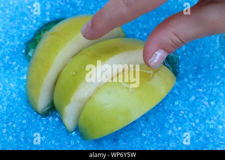 Poco dita di raggiungere per le mele immerso nel miele contro un blu sullo sfondo di zucchero Foto Stock