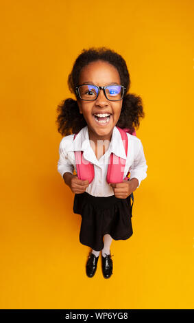 African American Schoolgirl ridere per fotocamera su sfondo giallo Foto Stock