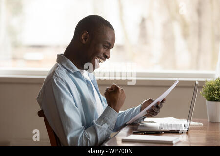 Emozionato biracial uomo sente euforici lettura lettera positiva Foto Stock