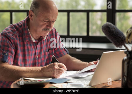 Senior uomo ispanico utilizzando una calcolatrice e calcolare le fatture al soggiorno Foto Stock