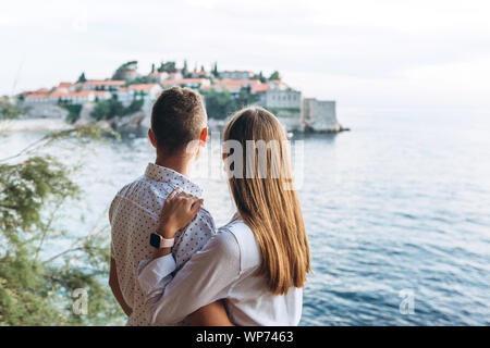 Un uomo e una donna potrete ammirare una splendida vista dell'isola di Sveti Stefan in Montenegro. Foto Stock