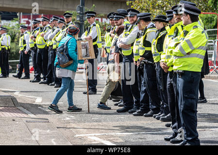 Piccola protesta donna anziana con cordone di polizia alla fiera internazionale delle armi DSEI (Defence & Security Equipment International), Excel, Londra, Regno Unito Foto Stock