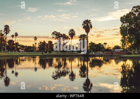 Fotografia analogica di un campo da golf lago durante il tramonto con palme riflessa nell'acqua. Sun City, Arizona. Foto Stock