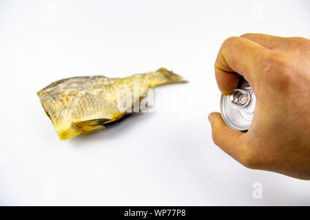 Pesci secchi e lattina di birra in mano isolati su sfondo bianco. La pesca.