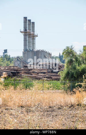 Un grande mulino di legname nel sud della Oregon con tre grandi pile di fumo e plles di tronchi di alberi pronti per l'elaborazione in primo piano. Foto Stock
