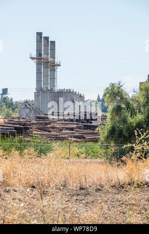 Un grande mulino di legname nel sud della Oregon con tre grandi pile di fumo e plles di tronchi di alberi pronti per l'elaborazione in primo piano. Foto Stock