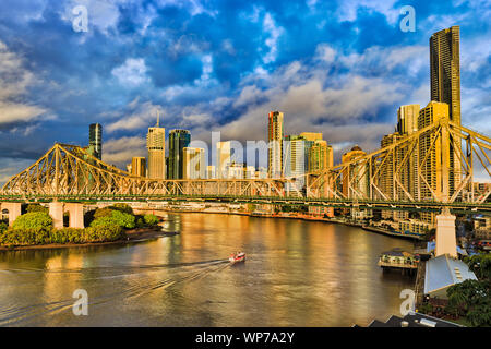 Storia ponte attraverso il fiume Brisbane a Brisbane città nella parte anteriore del CBD di alto-aumento di business e appartamento torri sotto il blu cielo nuvoloso e il traghetto passeggeri Foto Stock