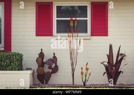 Dettaglio analogico fotografia di un off-white casa di mattoni con persiane rosse attorno alle finestre e stravaganti decorazioni in cantiere a Sun City, in Arizona. Foto Stock