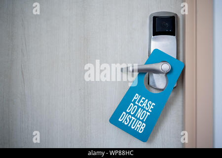 Porta chiusa della camera di albergo con si prega di non disturbare segno. Hotel porta appendiabiti Tags mockup. Foto Stock