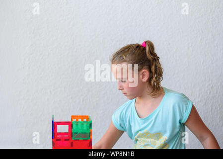 Bella ragazza adolescente giocando con un sacco di colorati di materia plastica in blocchi costruttore e costruisce la casa. Foto Stock