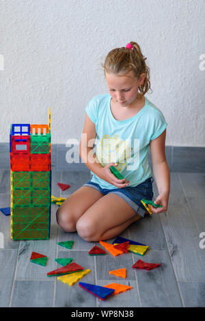 Bella ragazza adolescente giocando con un sacco di colorati di materia plastica in blocchi costruttore e costruisce la casa. Foto Stock