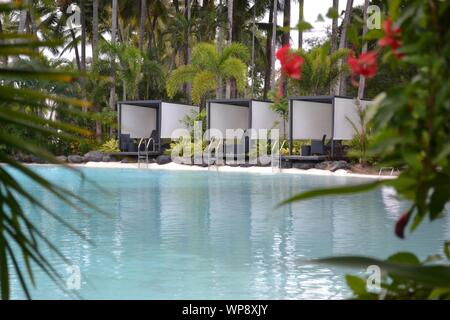 Lunga fila di vuoto lettini ordinatamente disposte in una linea su una spiaggia di Port Douglas, Queensland. Foto Stock