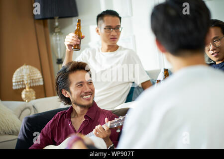 Giovani asiatici uomini adulti bere birra a casa Foto Stock