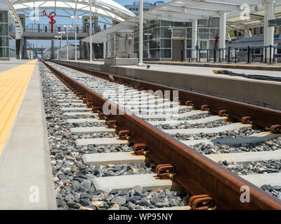 Close up di rusty railroad viaggi e ghiaia nella stazione ferroviaria moderna Foto Stock