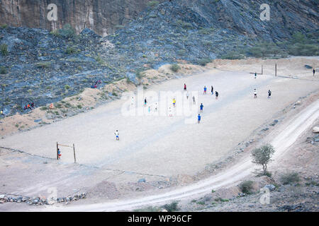 Gli uomini che giocano a calcio su un campo di calcio nelle montagne del deserto di Oman Foto Stock