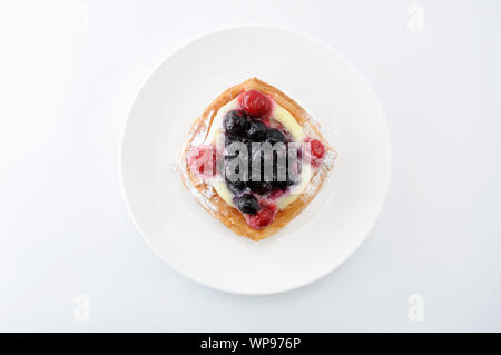 Mirtillo torta con crema pasticcera su una piastra isolata su sfondo bianco Foto Stock