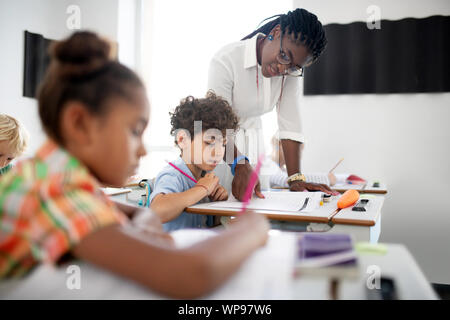 Curly boy ascolto di afro-americano di insegnante con gli occhiali Foto Stock