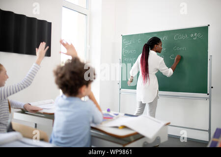 Di carnagione scura insegnante a scrivere sulla lavagna per bambini Foto Stock