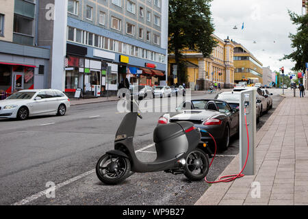 Scooter elettrici per la condivisione con stazione di ricarica su una strada di città Foto Stock
