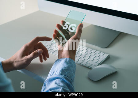 Un uomo utilizza un avveniristico telefono trasparente con 5G Foto Stock