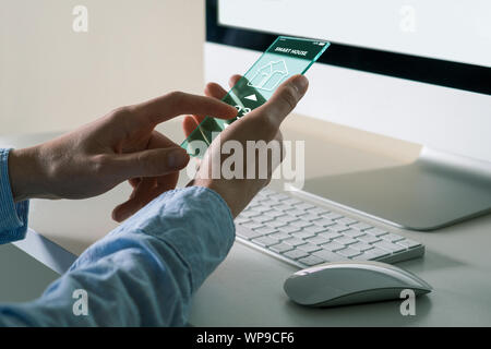 Un uomo utilizza un avveniristico telefono trasparente con applicazione per il controllo smart house. Foto Stock