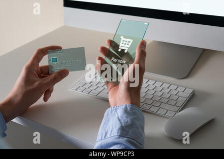 L'uomo utilizza un avveniristico telefono trasparente e una carta di credito per il pagamento on-line Foto Stock